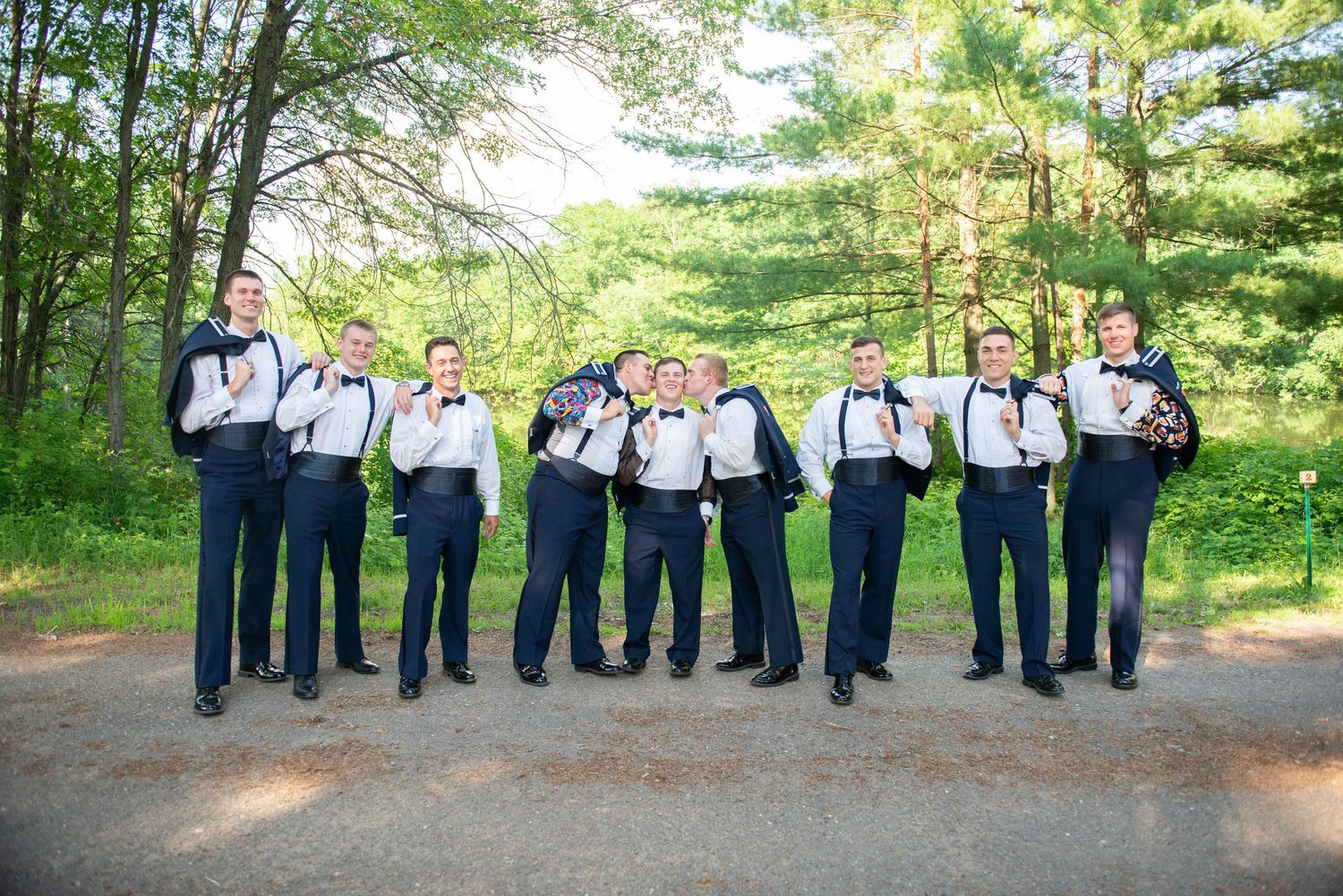 Wedding party in navy and white attire posed along a tree-lined path. Zimmerman MN Weddings