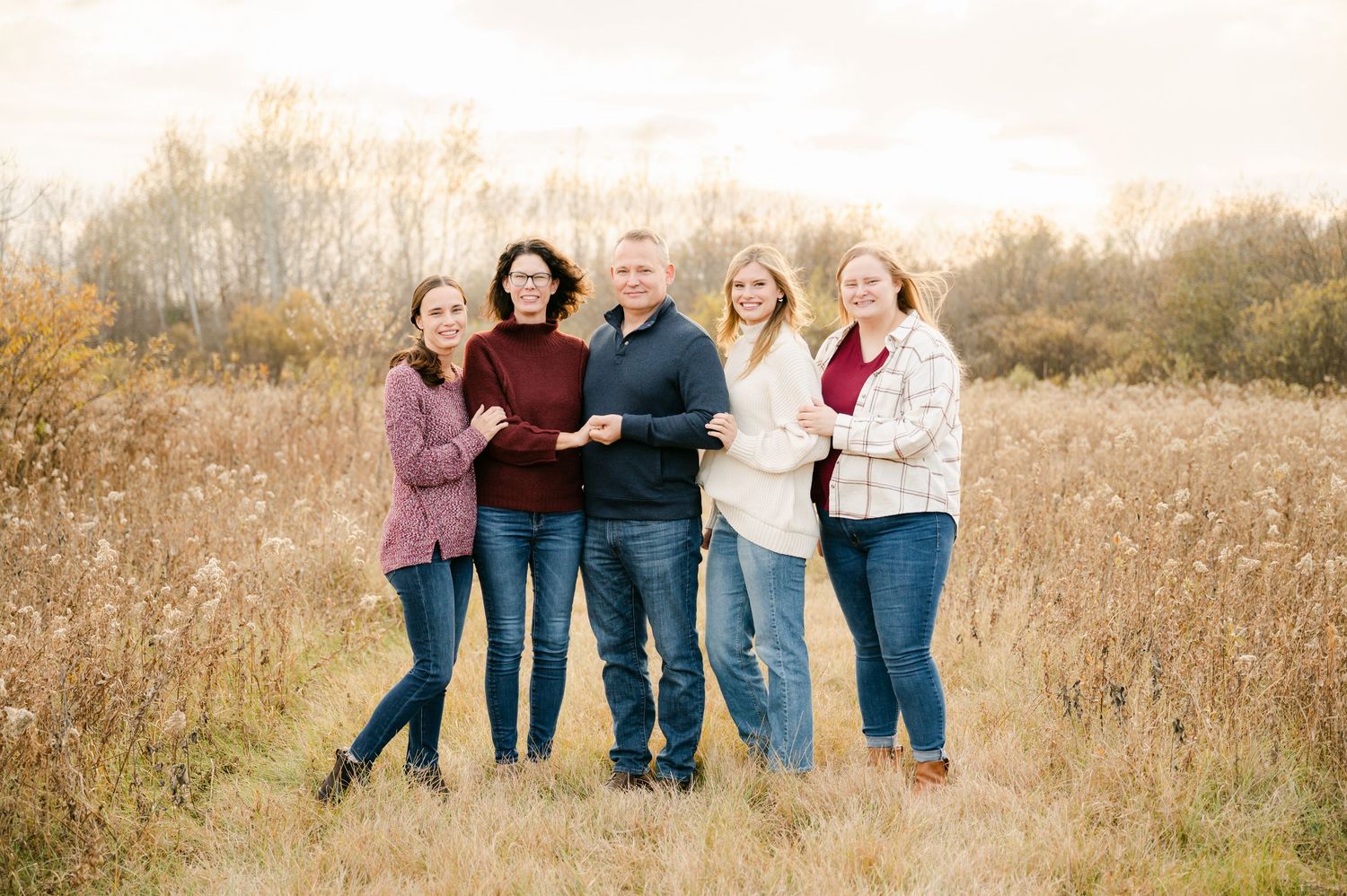 A group of people pose together on a golden autumn field, shown in multiple casual outdoor portrait compositions.