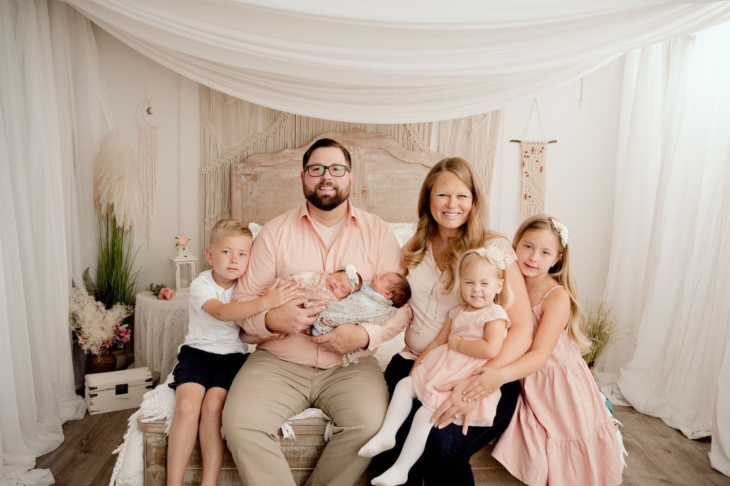 Family of six posing for a professional portrait in a soft, elegant studio setting with white draping.