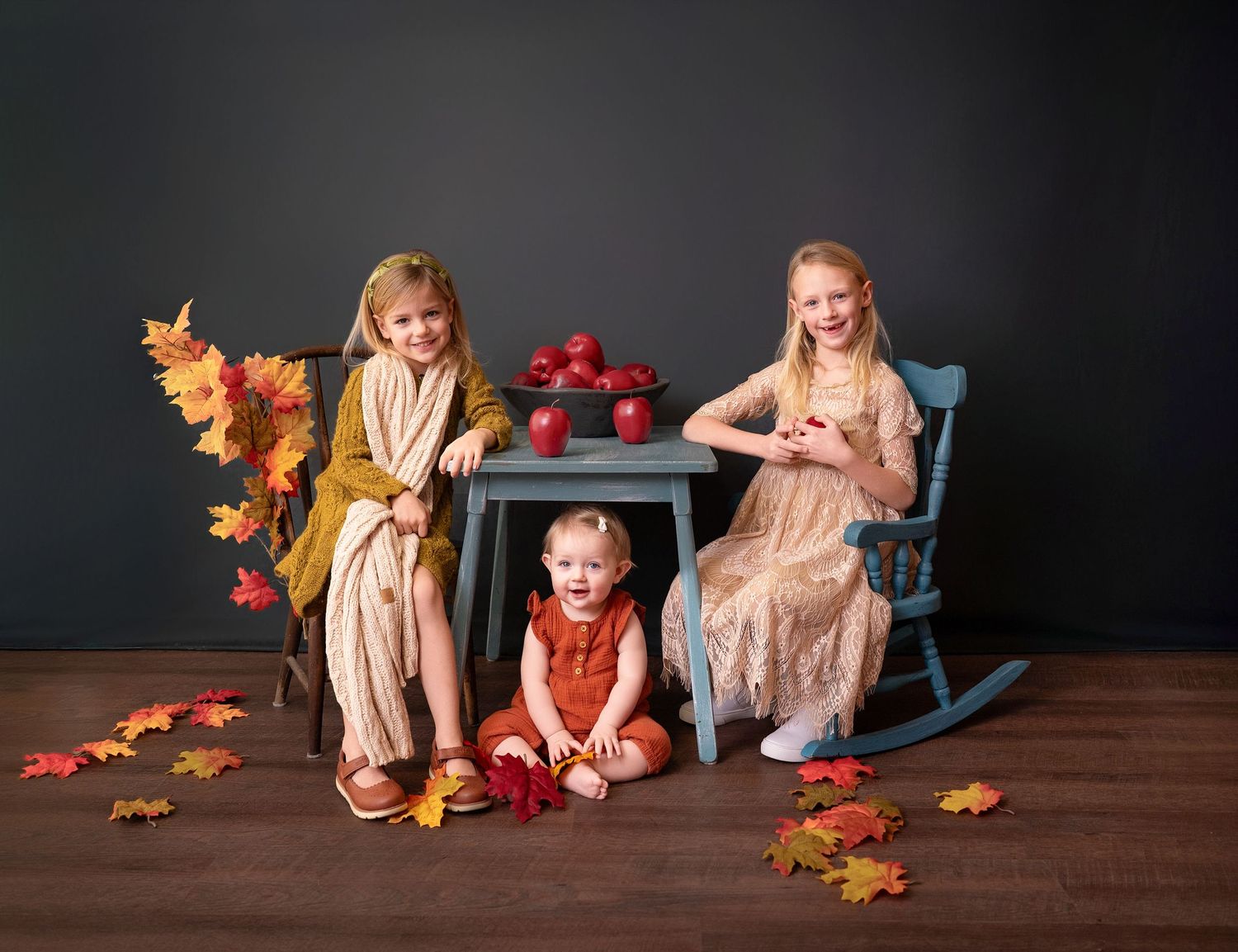 A series of fall-themed photos showing children posing with autumn leaves and decorative pumpkins against a dark backdrop.