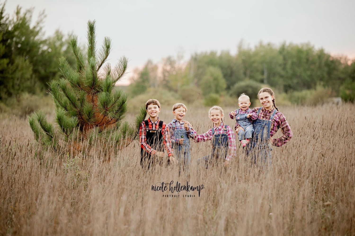 Family group stands together in tall prairie grass during golden hour.