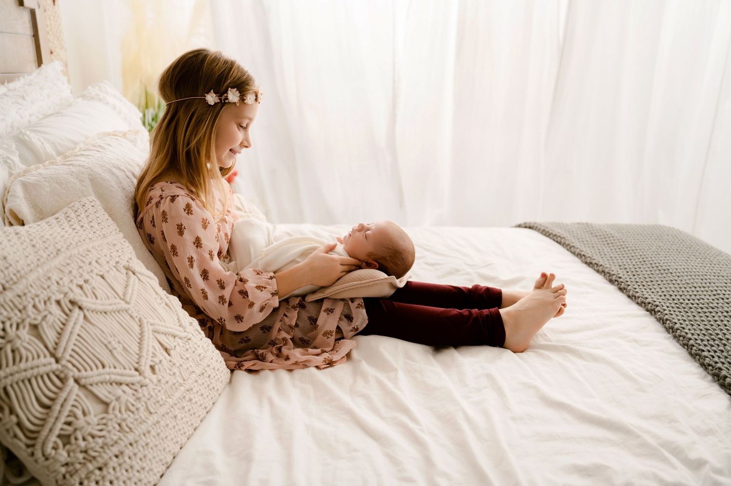 Parent reads bedtime story to child while snuggling together under soft white bedding.