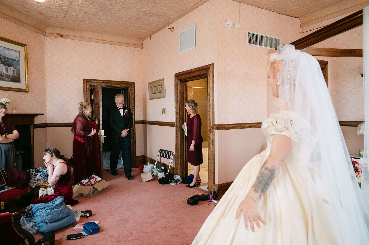 Central MN Wedding Photos | Bride in vintage champagne wedding dress with veil meeting suited father in decorated room before ceremony.