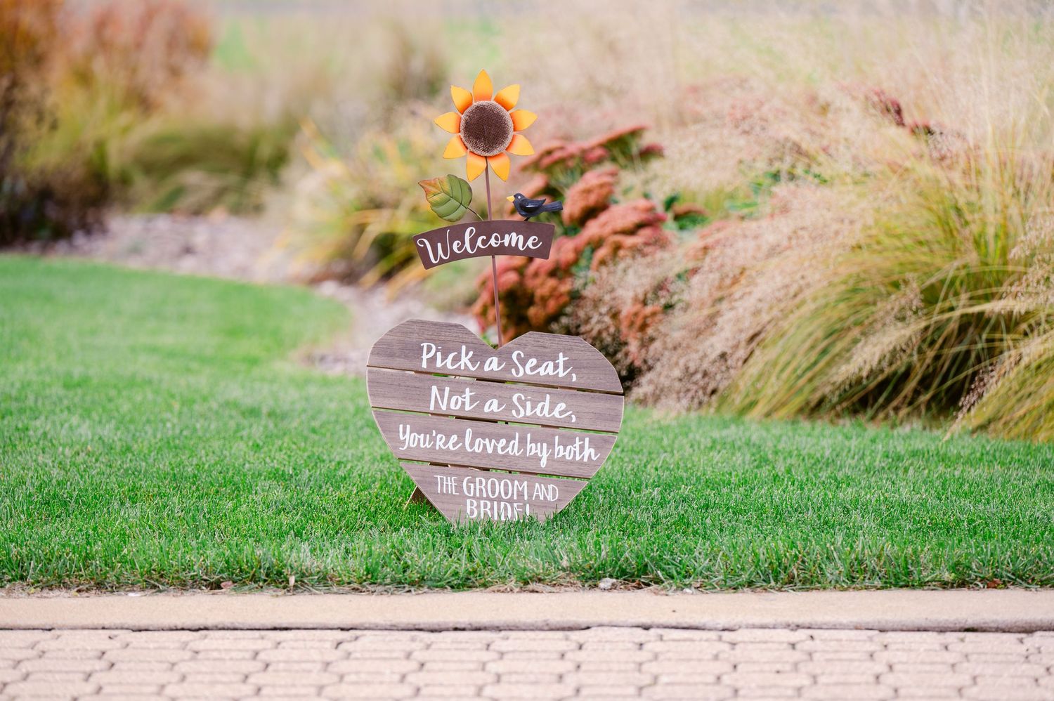 Central MN Wedding Photos | Rustic heart-shaped wedding welcome sign with sunflower reads Pick a Seat Not a Side.