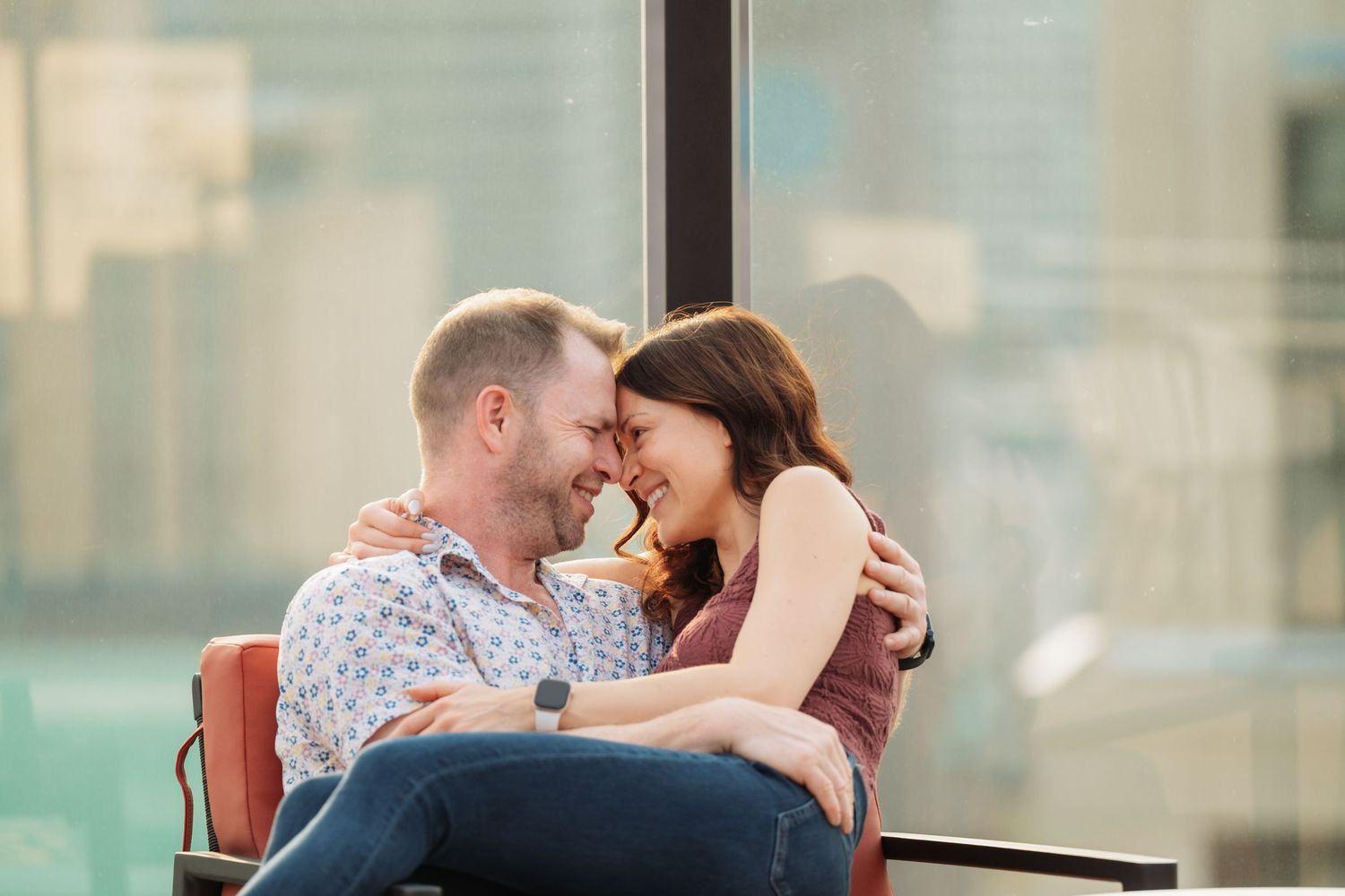 A couple shares an intimate moment on a modern rooftop terrace with glass railings.