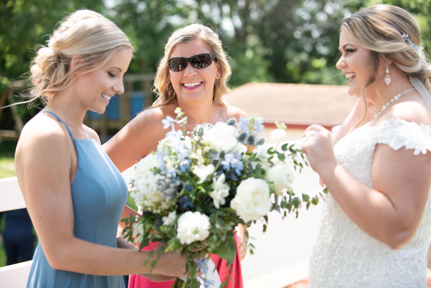 A group celebrating outdoors with white and blue dresses against a sunny background. Zimmerman MN Weddings
