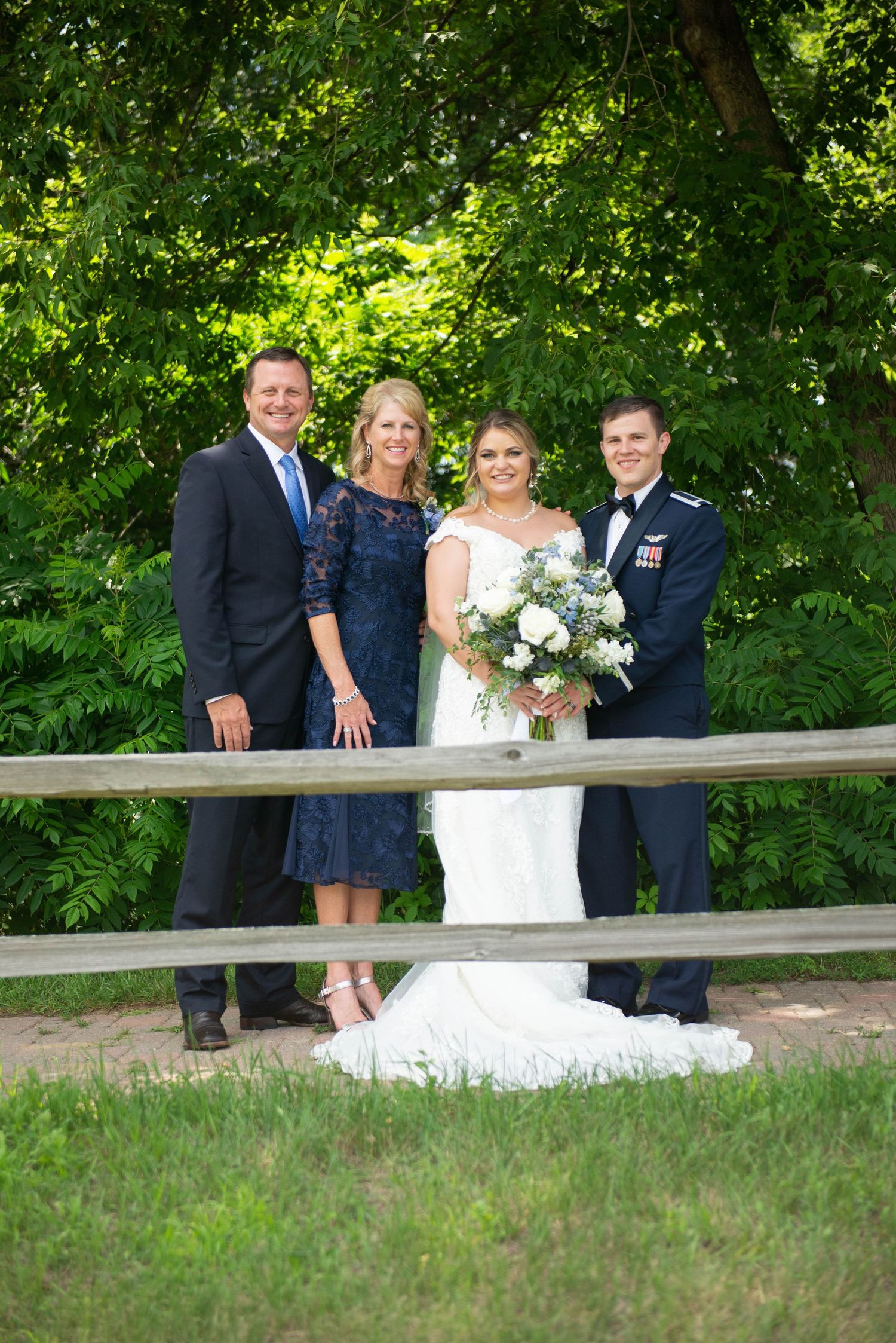 Family portrait on a wooden bridge surrounded by lush greenery. Zimmerman MN Weddings