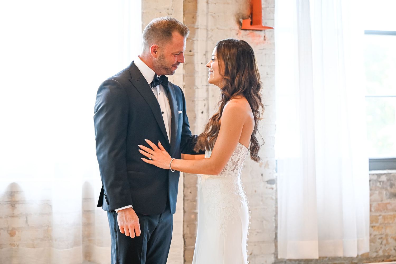 A couple shares a special moment in a bright industrial-style room with brick walls.