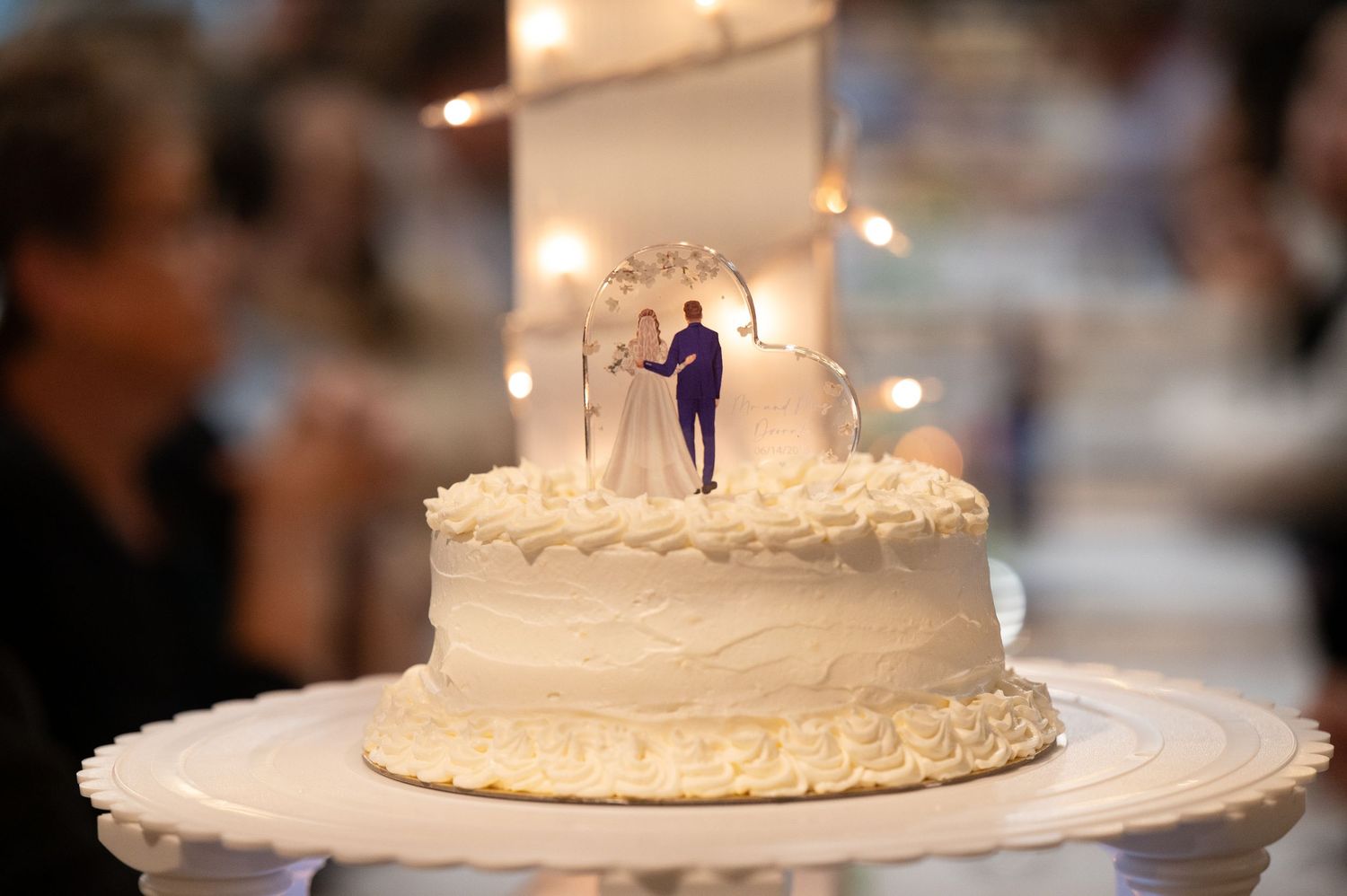 Detail shots of a traditional white wedding cake with decorative frosting patterns and candle lighting at a reception.