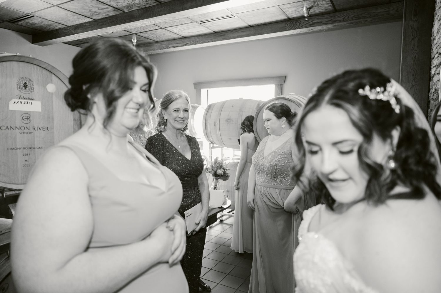 Central MN Wedding Photos - Black and white photo of brides and bridesmaids laughing together before wedding ceremony at winery venue.