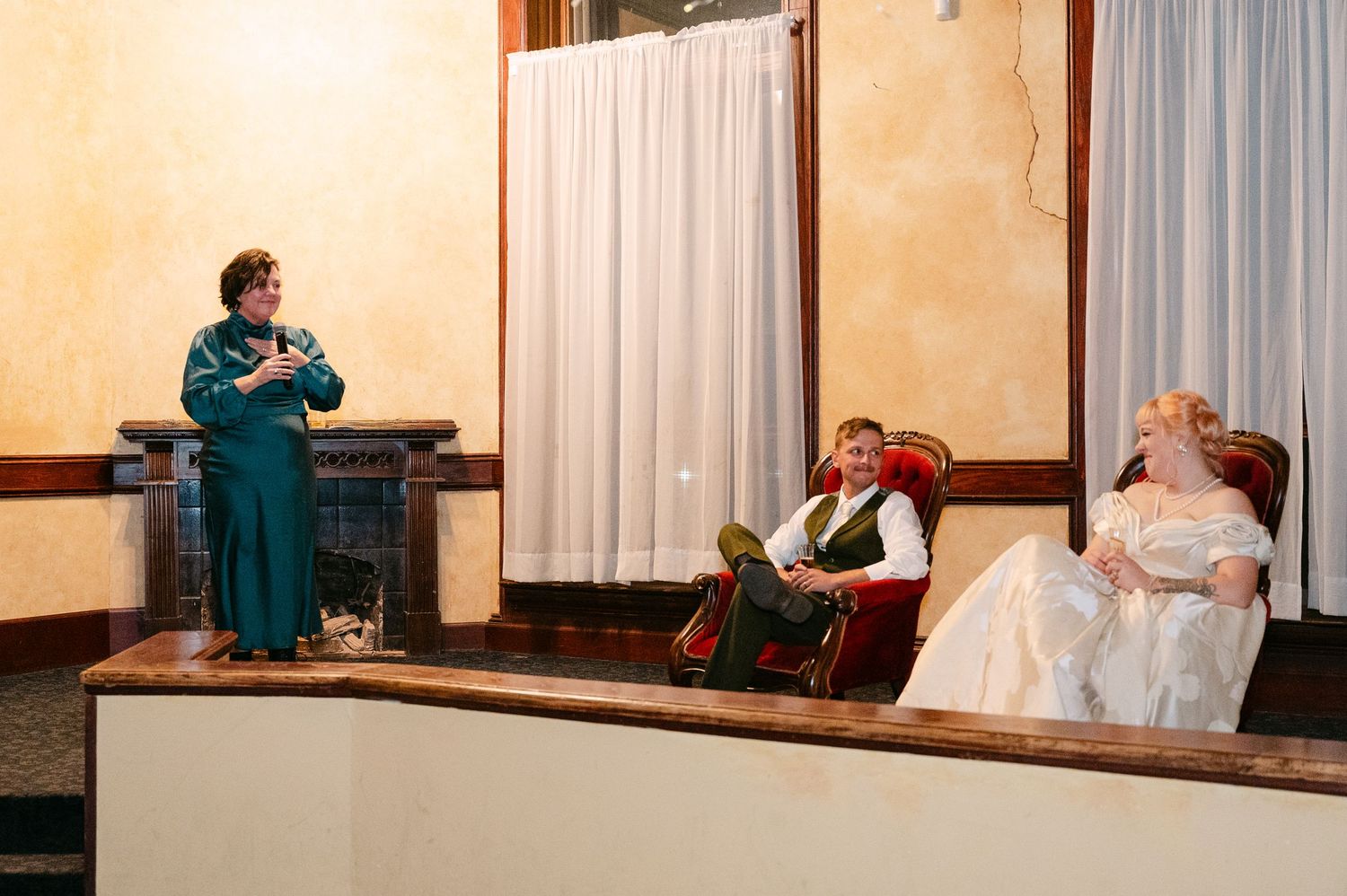 Central MN Wedding Photos | Wedding officiant in teal dress speaking to seated bride and groom.