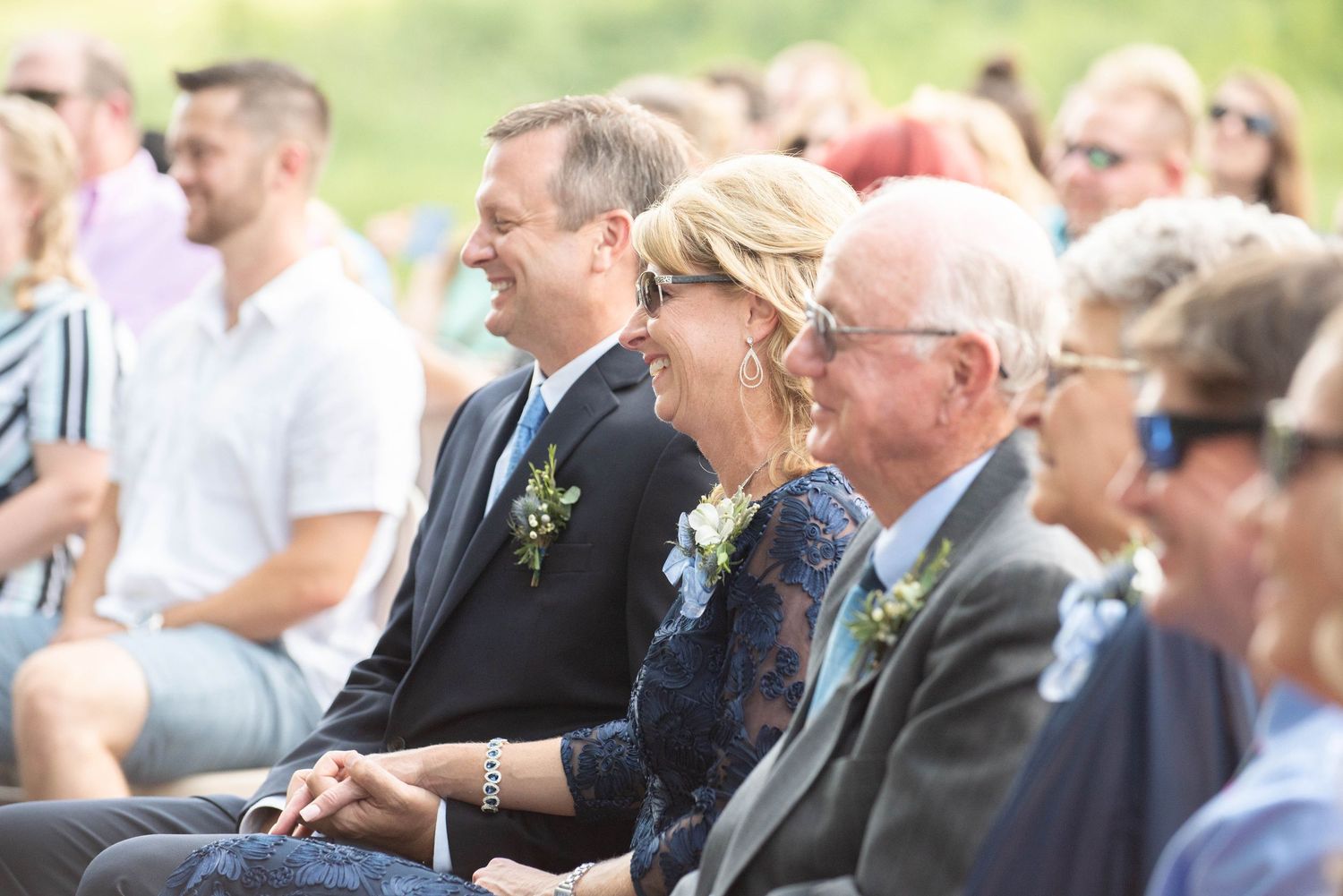 Guests are seated in white chairs watching an outdoor event on a sunny afternoon. Zimmerman MN Weddings