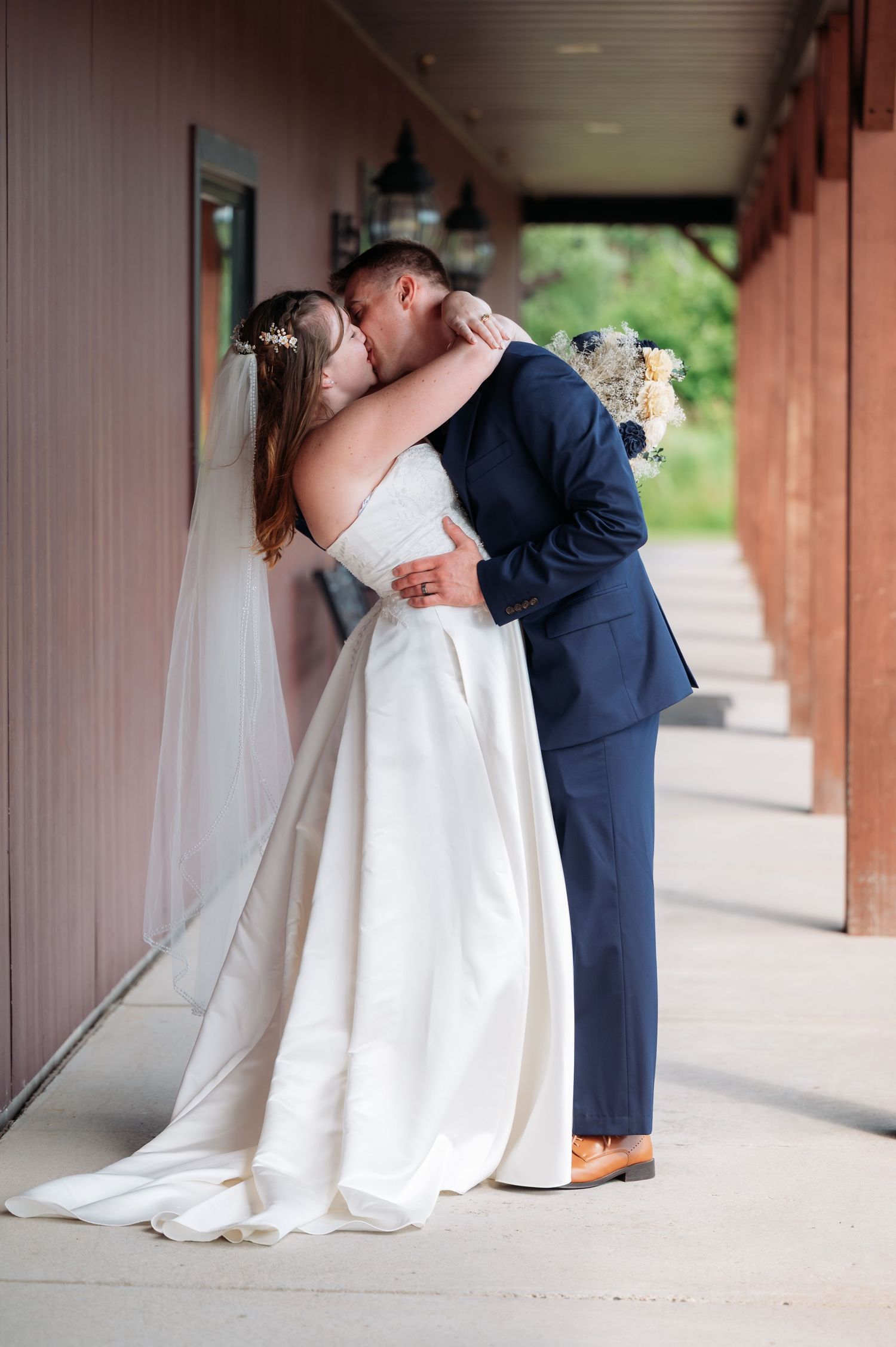 Romantic wedding couple sharing intimate moments in a covered outdoor corridor at Northern Lights near Milaca MN..
