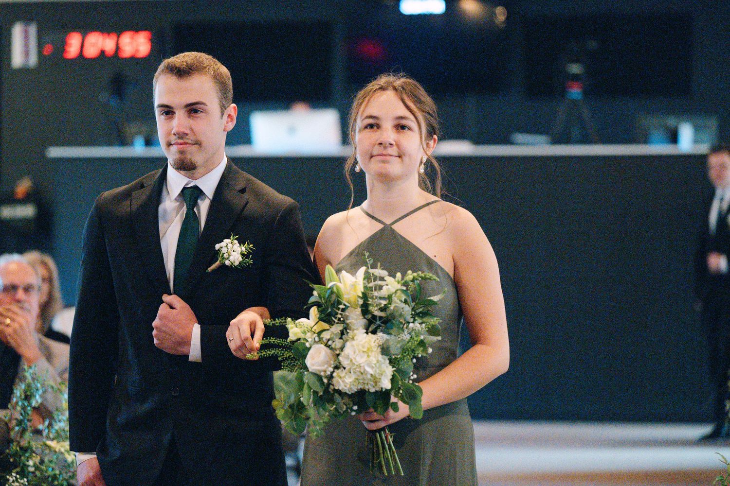 Wedding party members in formal attire standing in line during indoor ceremony.