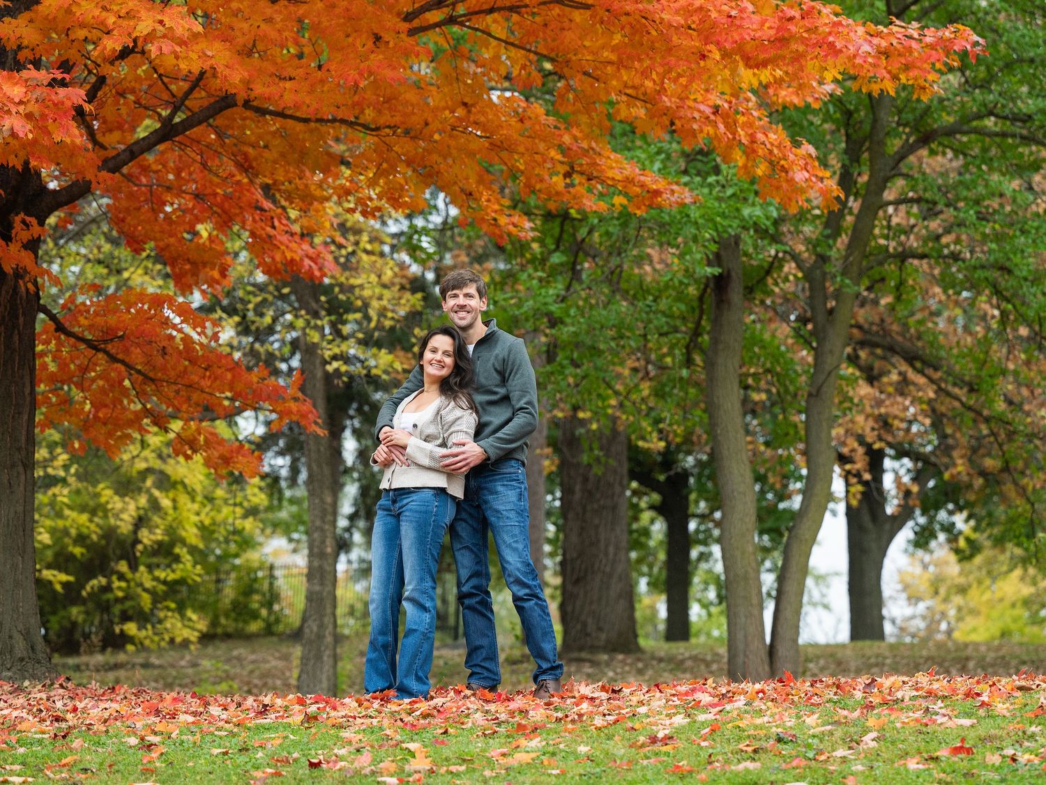 Couple enjoying a tender moment in a park with orange and red fall foliage at Lake Como. Engagement Sessions Minnesota.