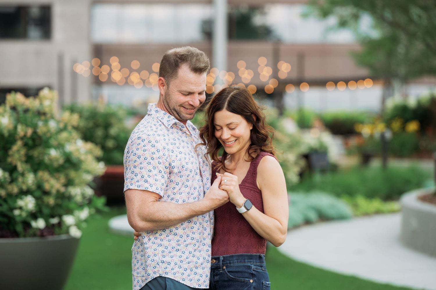 A couple shares a romantic moment dancing together in a garden setting during golden hour.