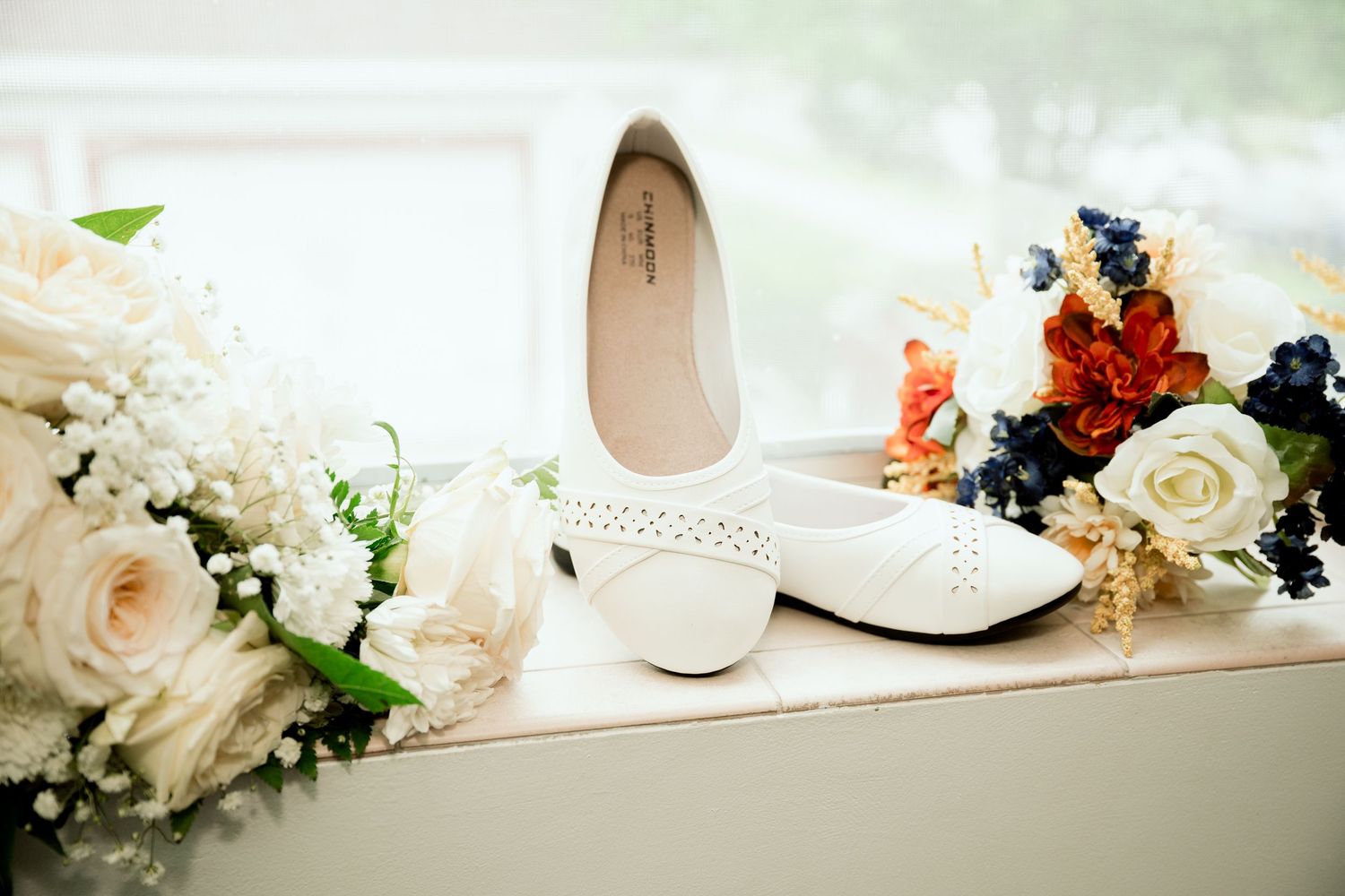 Wedding details including white flowers, candles, and personal decor items arranged on tables for a romantic reception setting.