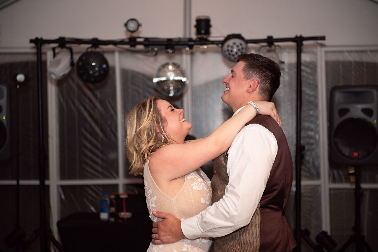Couples dancing together at an indoor wedding reception with dim lighting.
