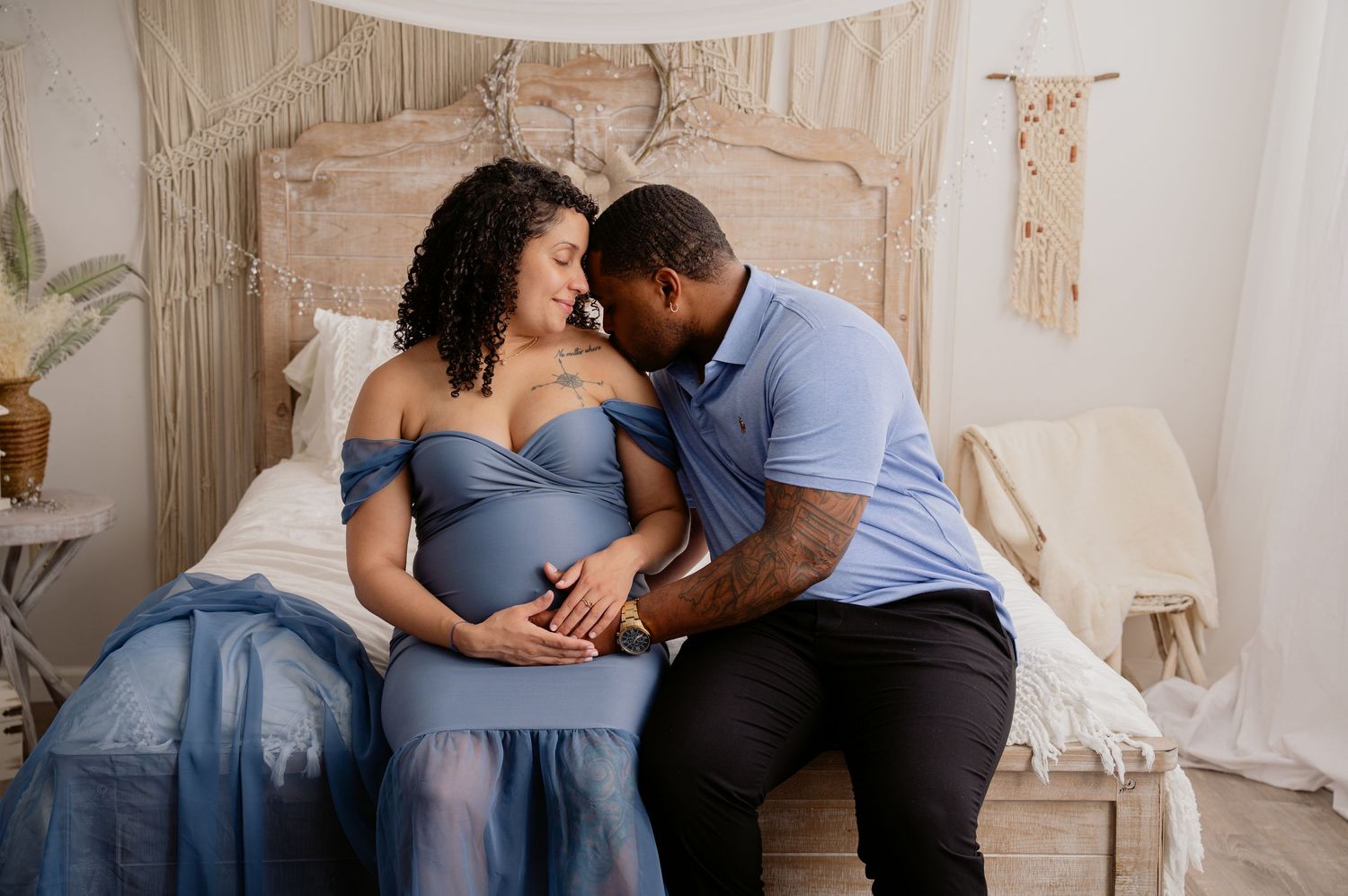 A romantic couple in blue attire shares an intimate moment against a light neutral background.