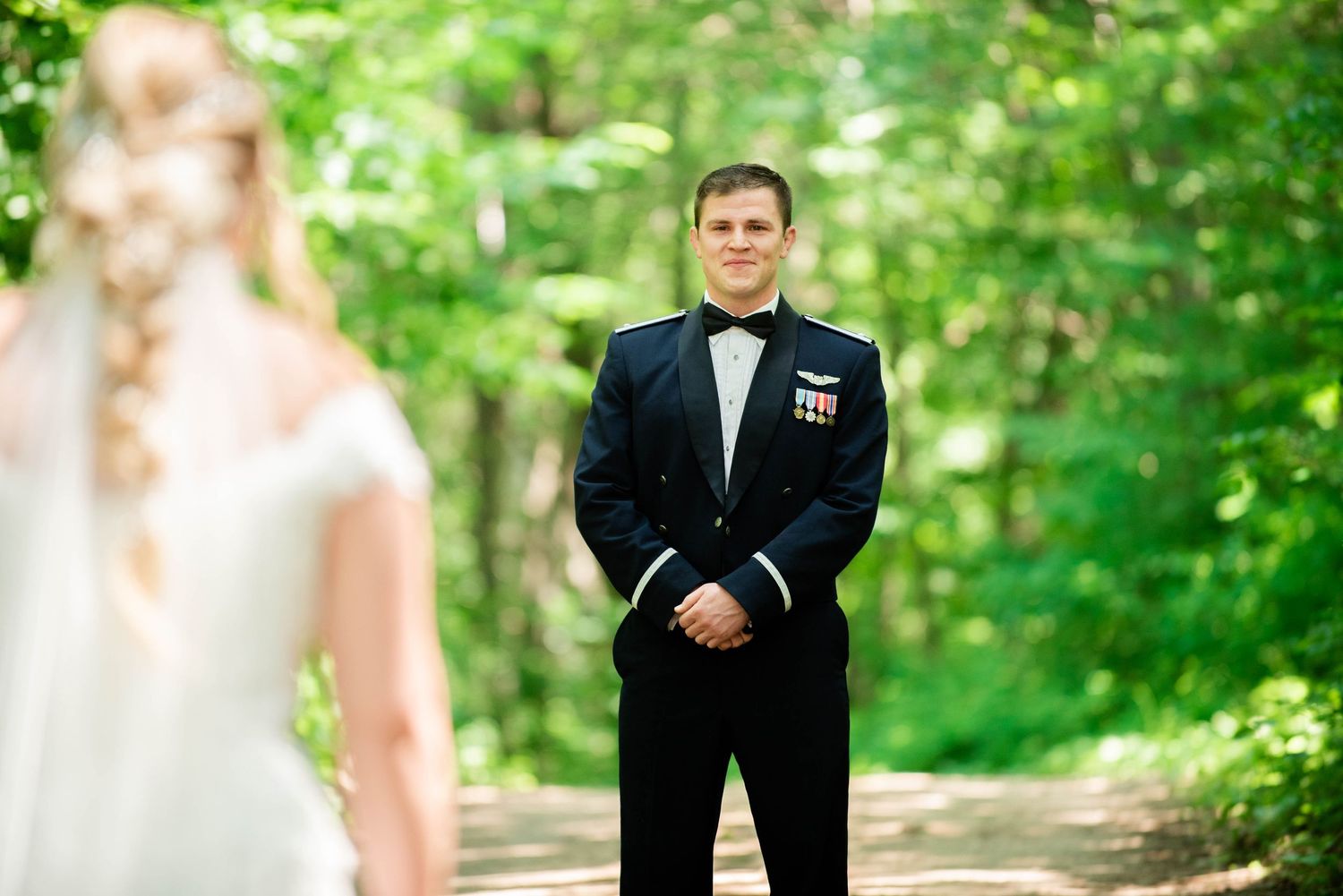Military wedding couple shares first look moment in a lush green forest setting. Zimmerman MN Weddings