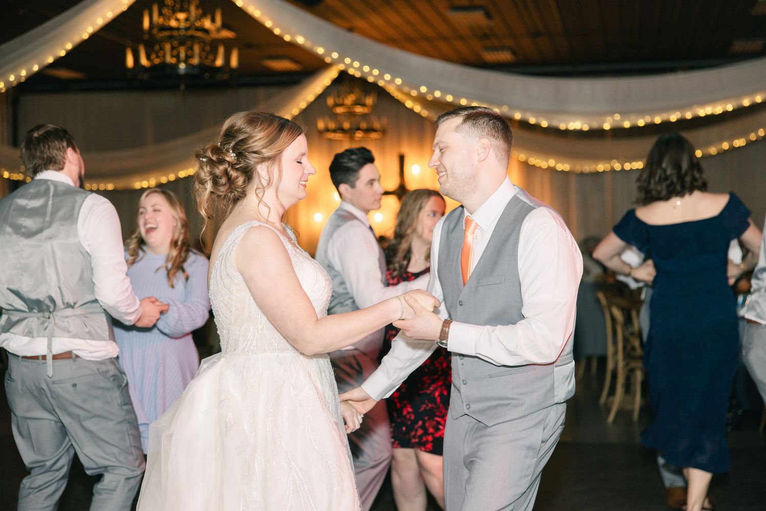 Bride and groom share a dance surrounded by guests at their wedding reception.