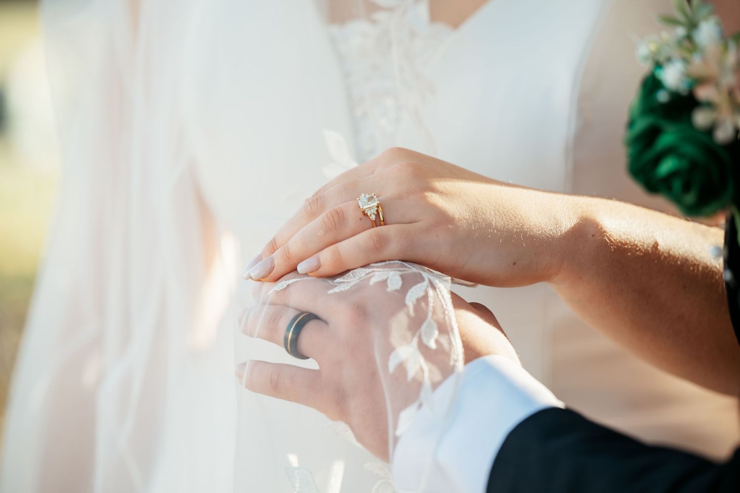 Close up of hands exchanging wedding rings during ceremony in soft natural light.