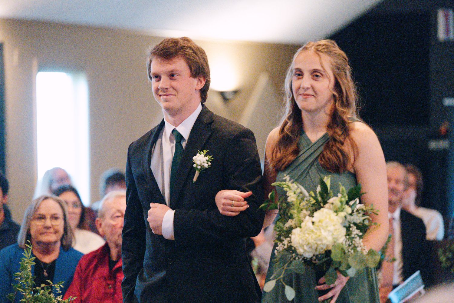 Wedding party members stand together during ceremony with elegant floral arrangements and formal attire.