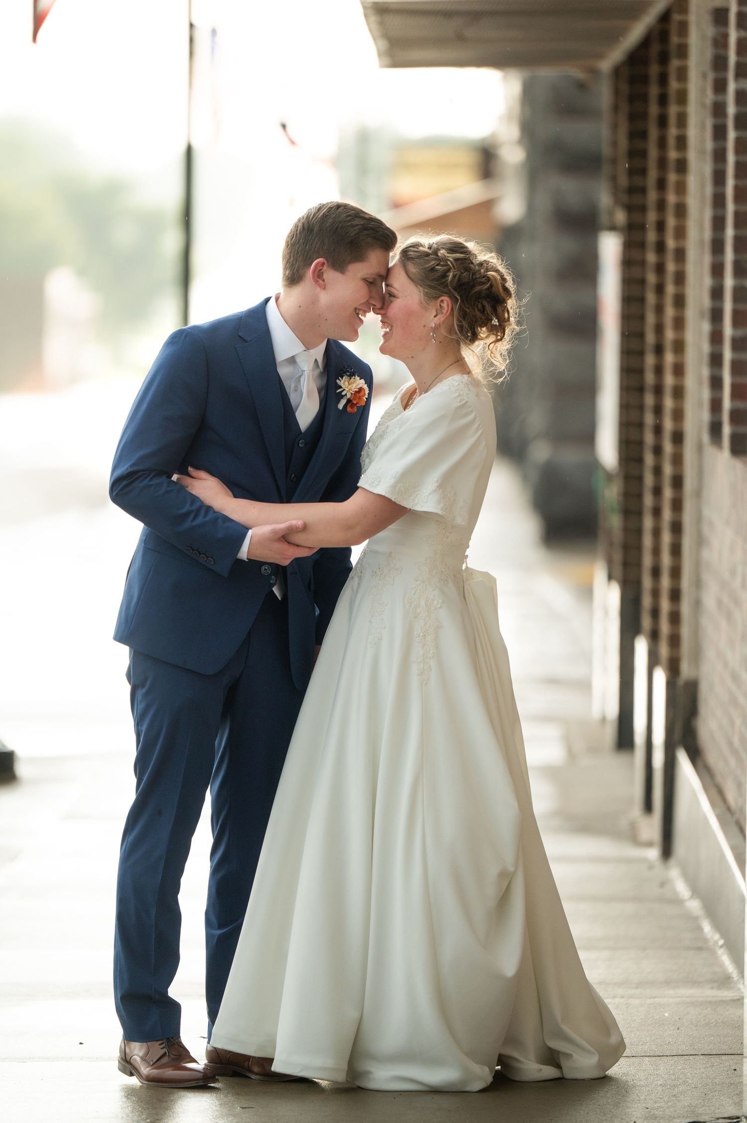 Romantic wedding moment under covered walkway with classic navy and white attire.