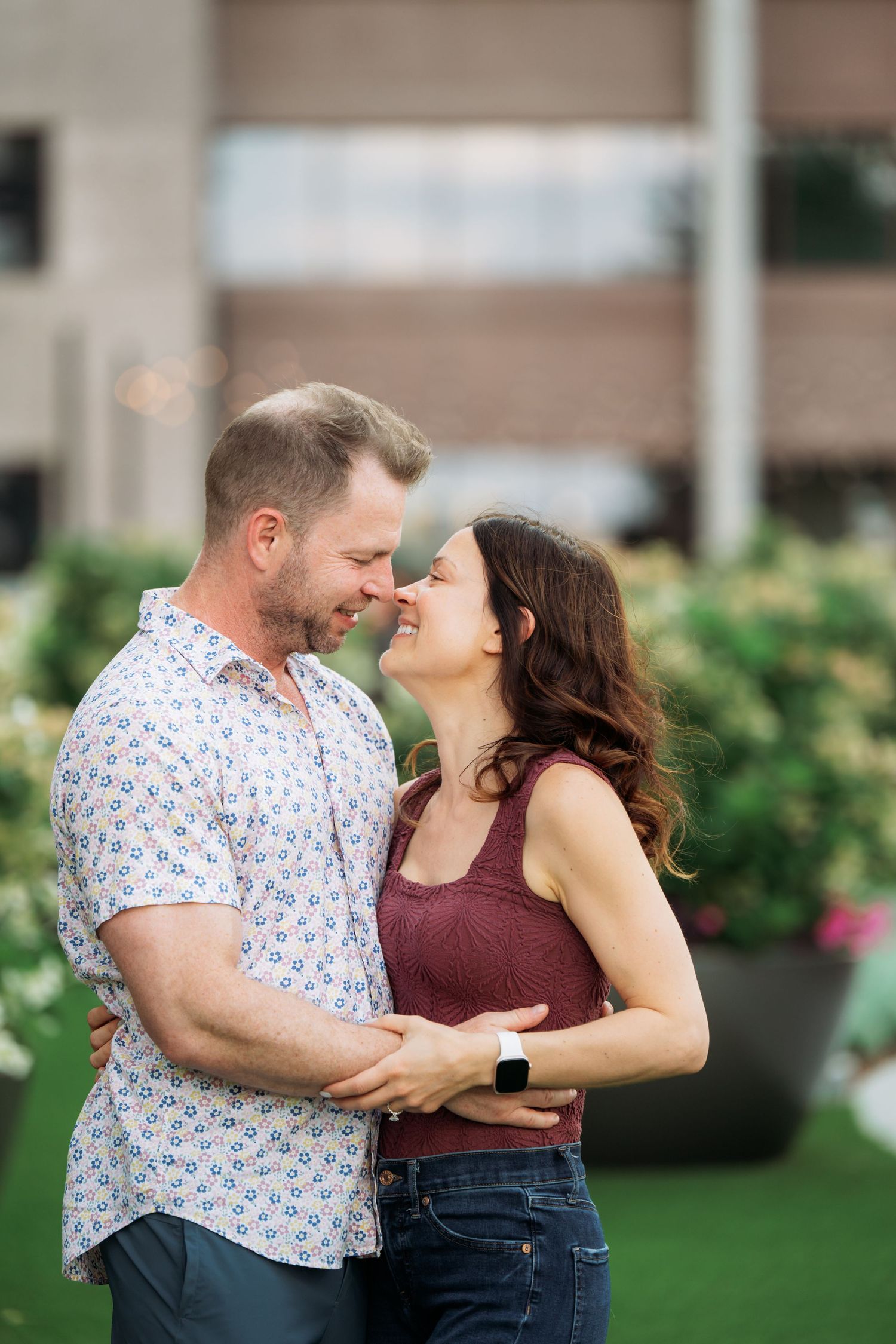 A romantic couple embraces while dancing together on a grassy area near blooming gardens.