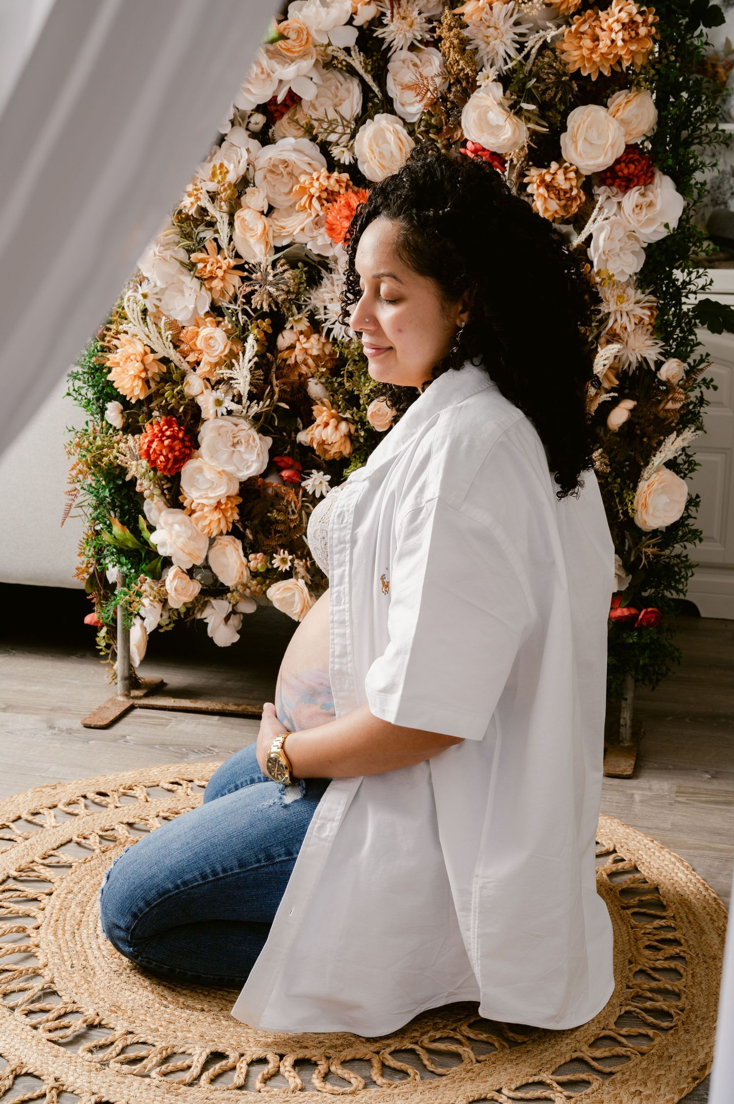 A side profile view shows a white shirt and jeans against a backdrop of peach and white floral arrangements and foliage.