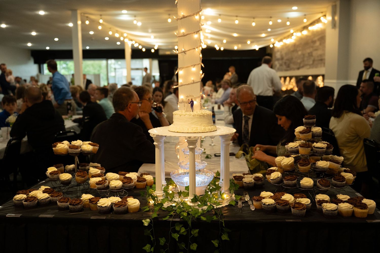 Restaurant diners enjoying a meal in a cozy space illuminated by warm string lights and chandeliers.