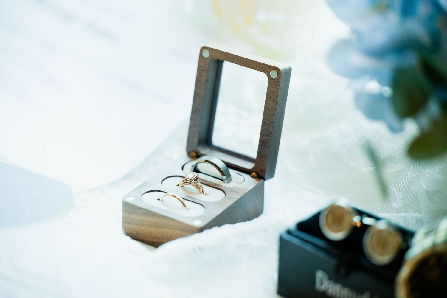 Elegant wedding rings displayed in a wooden box with mirror lid, showcasing gold bands for a wedding ceremony.