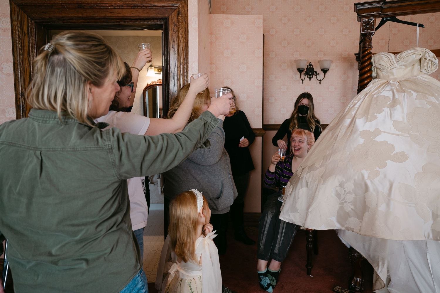 Central MN Wedding Photos | Wedding guests photograph a bridal gown displayed on a hanger in an elegant room.