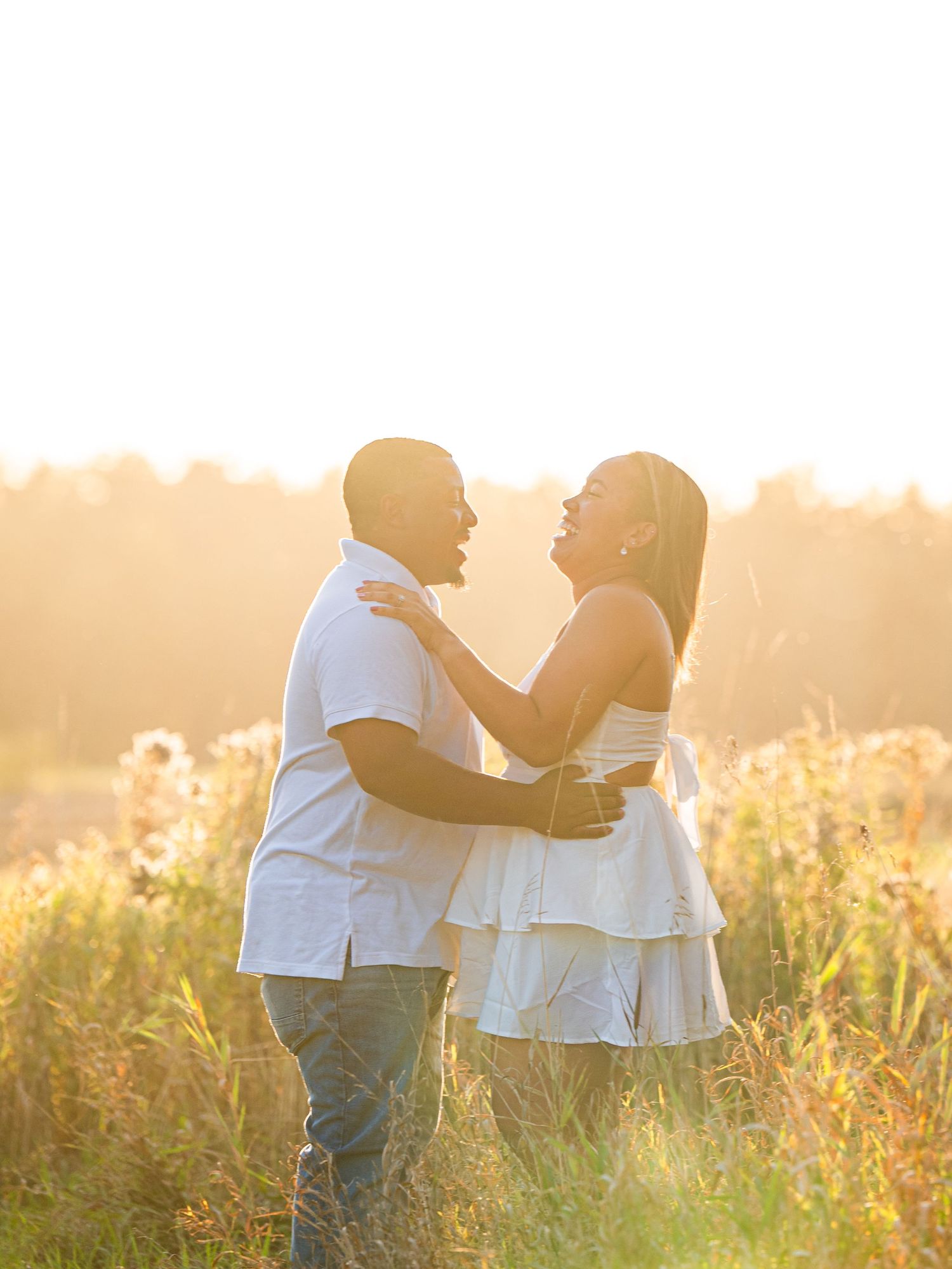 Central Minnesota Best Engagement Photographer - Couple embracing in golden sunlit field during sunset, wearing white outfits