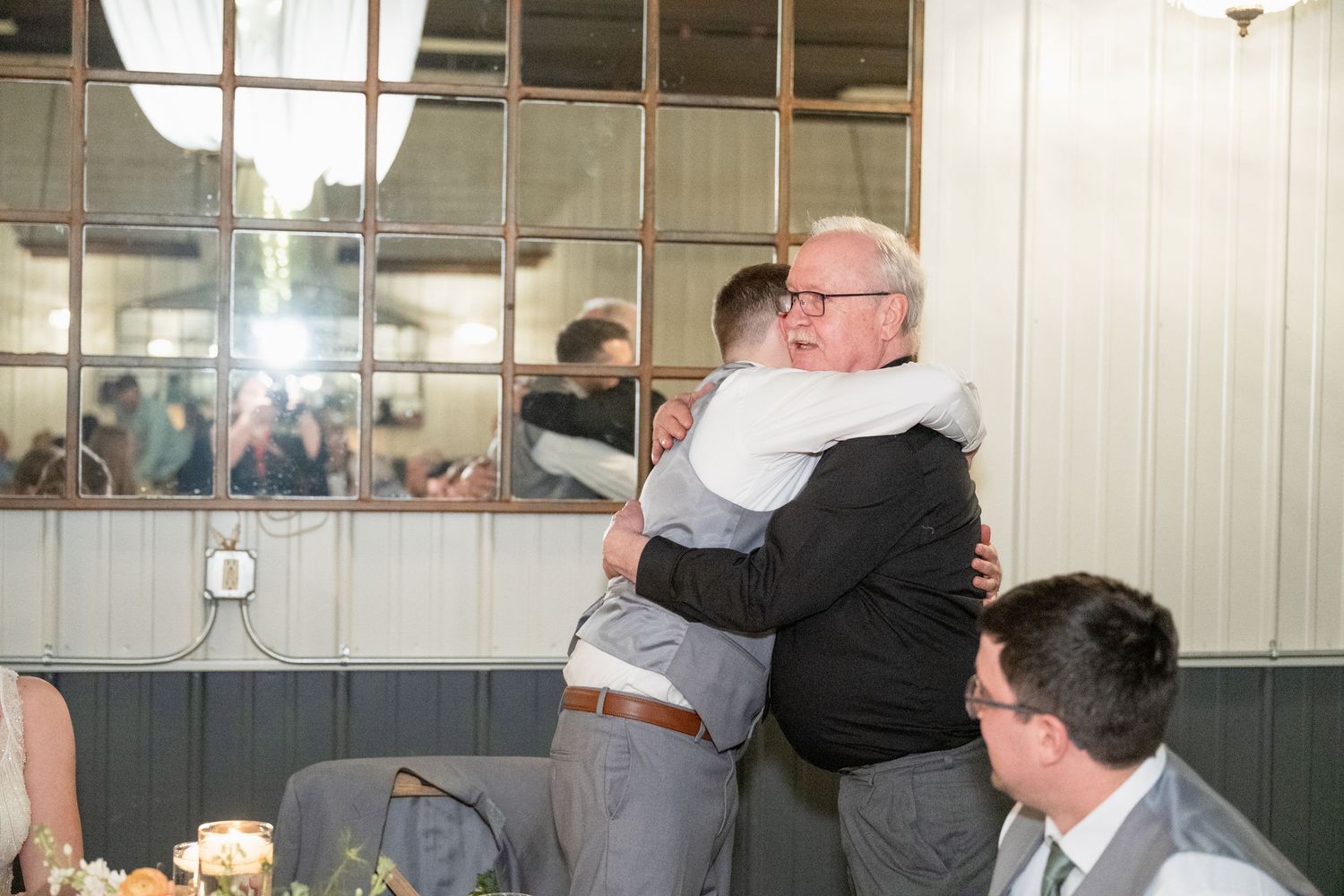 Emotional wedding moment as two men share a heartfelt hug at the reception.