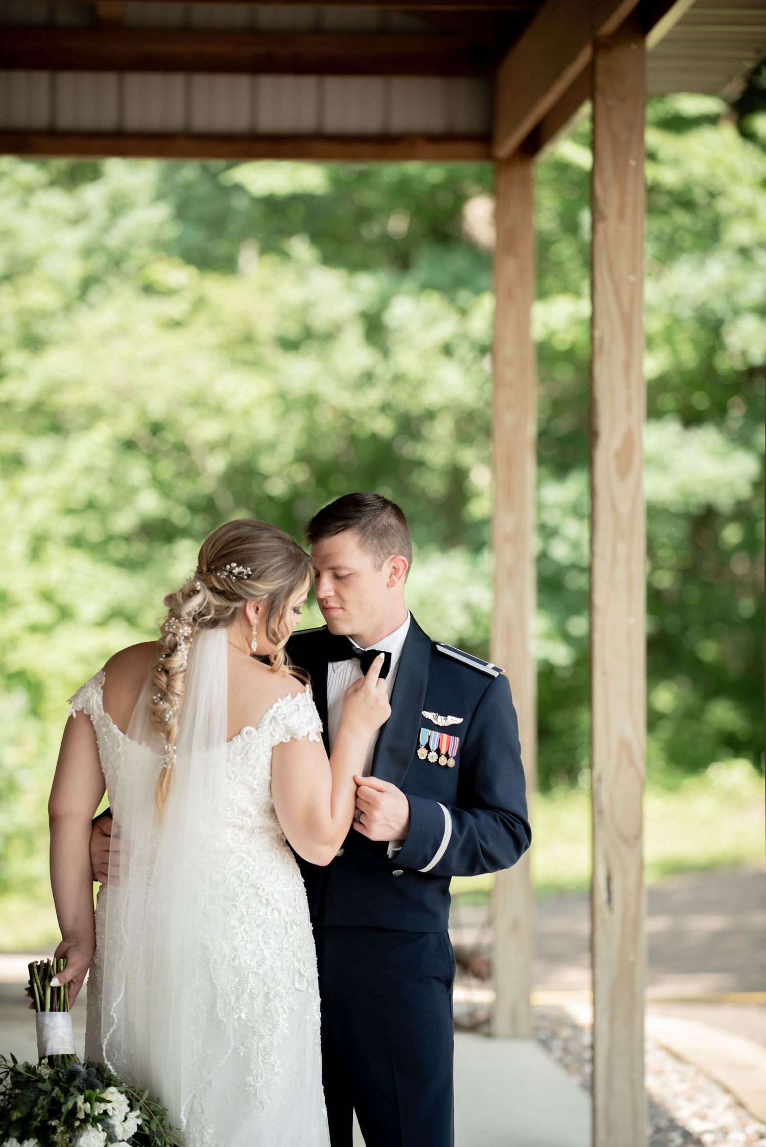 Intimate wedding moment shared under wooden pavilion with military dress uniform and lace gown. Zimmerman MN Weddings