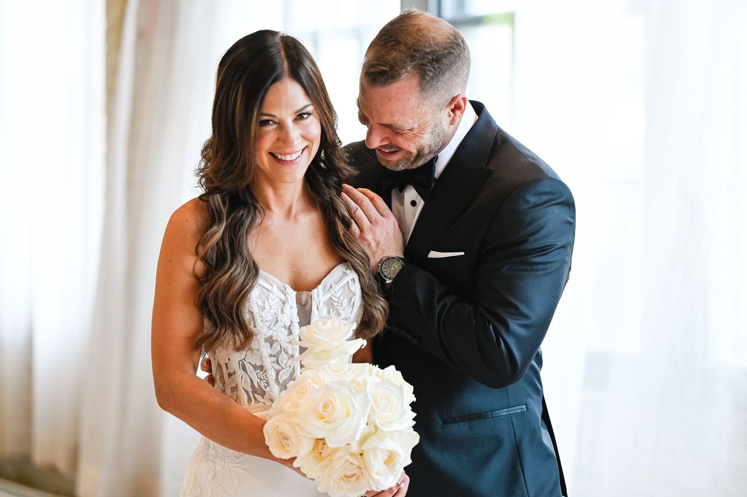 Romantic wedding moment captured in bright natural light with white floral bouquet.