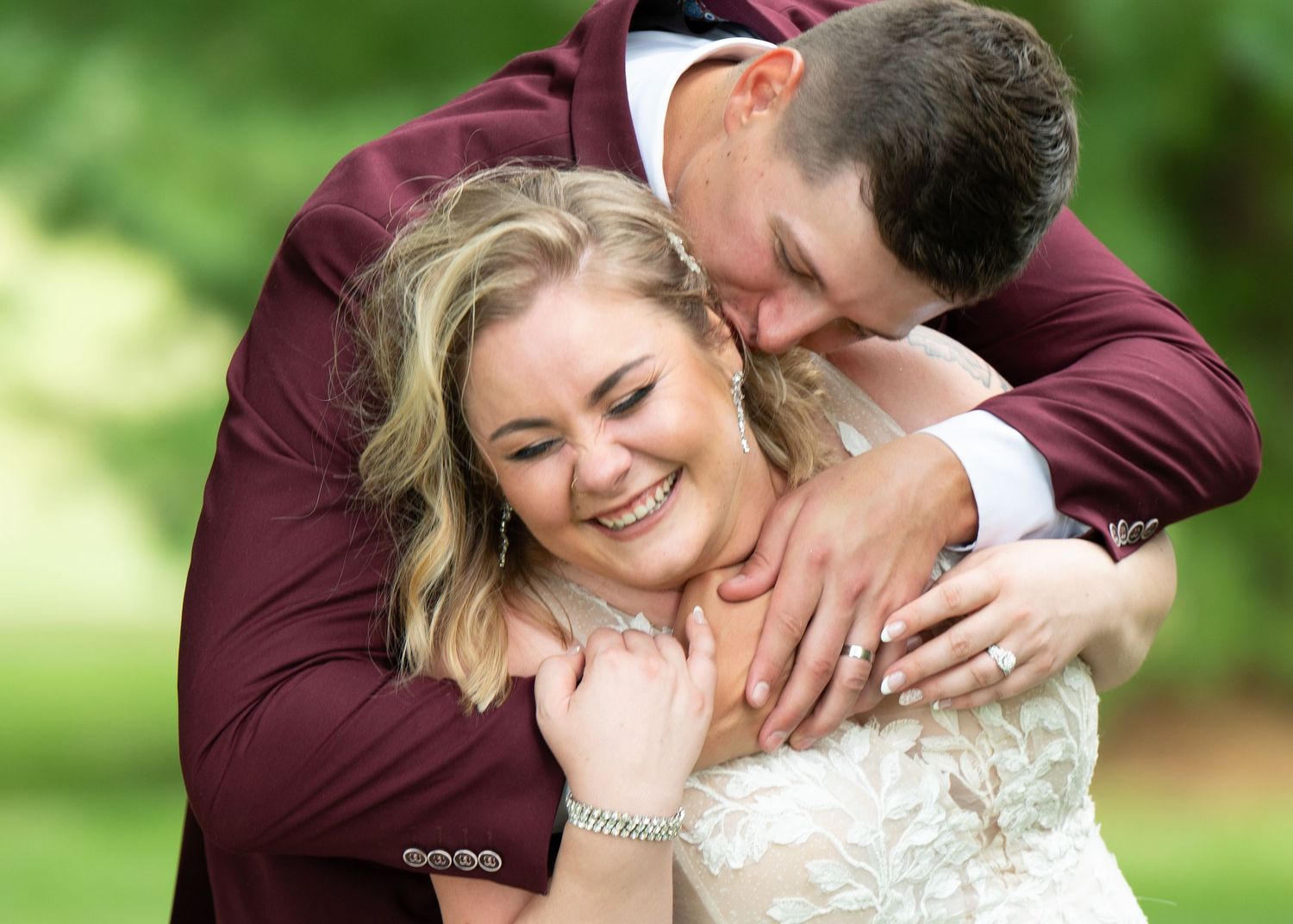 Central MN Wedding Photos - Bride & groom sharing a joyful embrace outdoors, groom kissing bride's cheek on their wedding day.