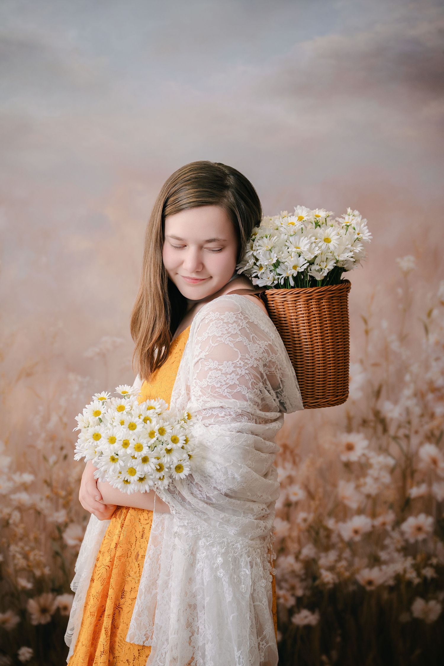 Dreamy portrait of someone in a lace and mustard colored dress holding daisies with a wicker basket in soft lighting.