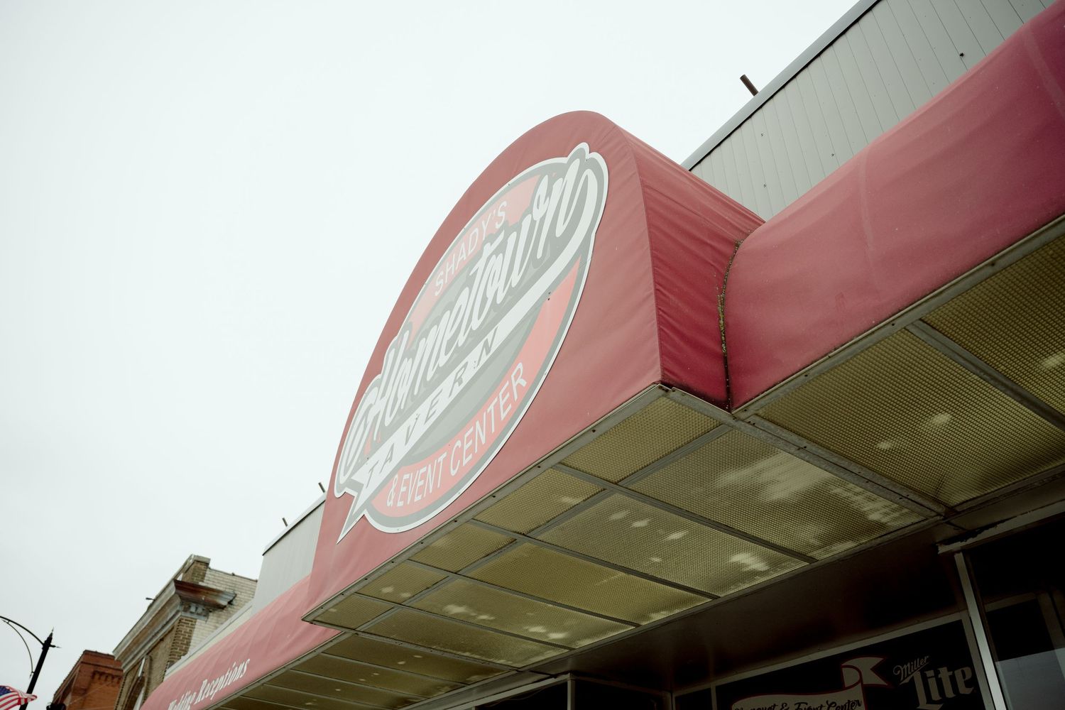Low angle view of a vintage pink storefront with retro signage and an illuminated overhang canopy.