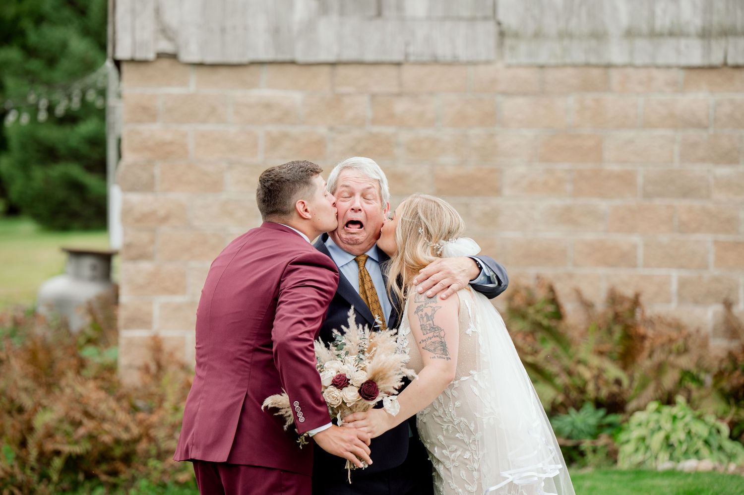 Candid emotional moment shared during wedding portraits by rustic stone wall.