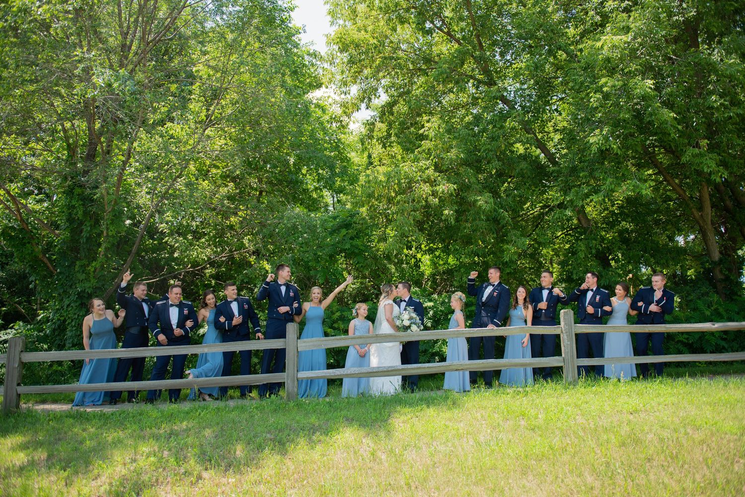 Wedding party lined up along fence for formal group photos in garden setting. Zimmerman MN Weddings