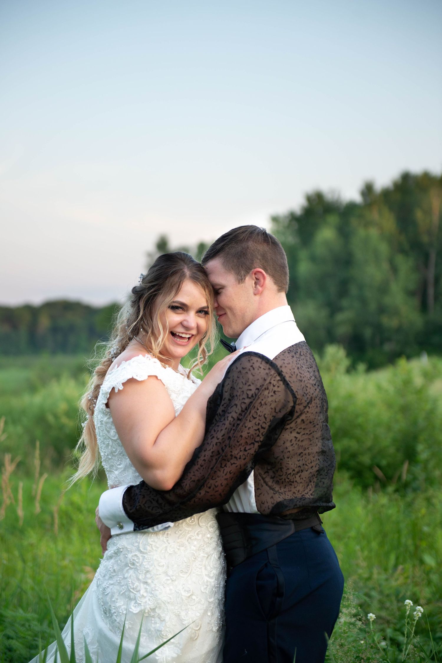 Intimate wedding portrait in a lush green field with soft natural lighting. Zimmerman MN Weddings