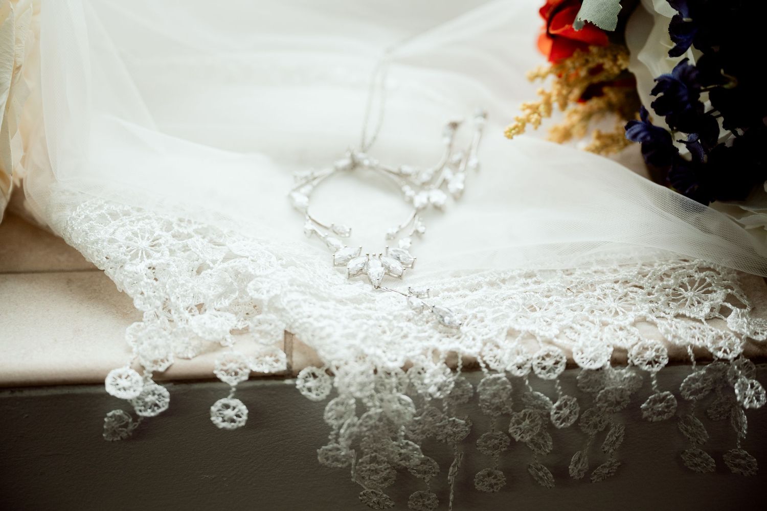 Delicate white lace detail with floral embroidery and beading on wedding dress fabric.