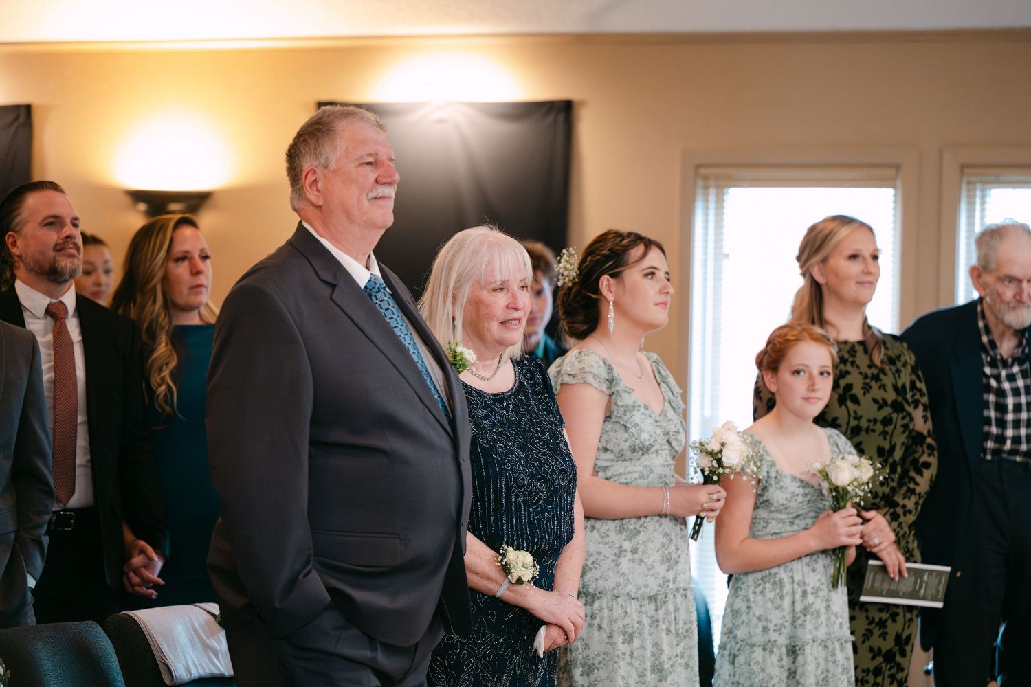 Wedding guests and family members lined up inside venue during formal celebration.
