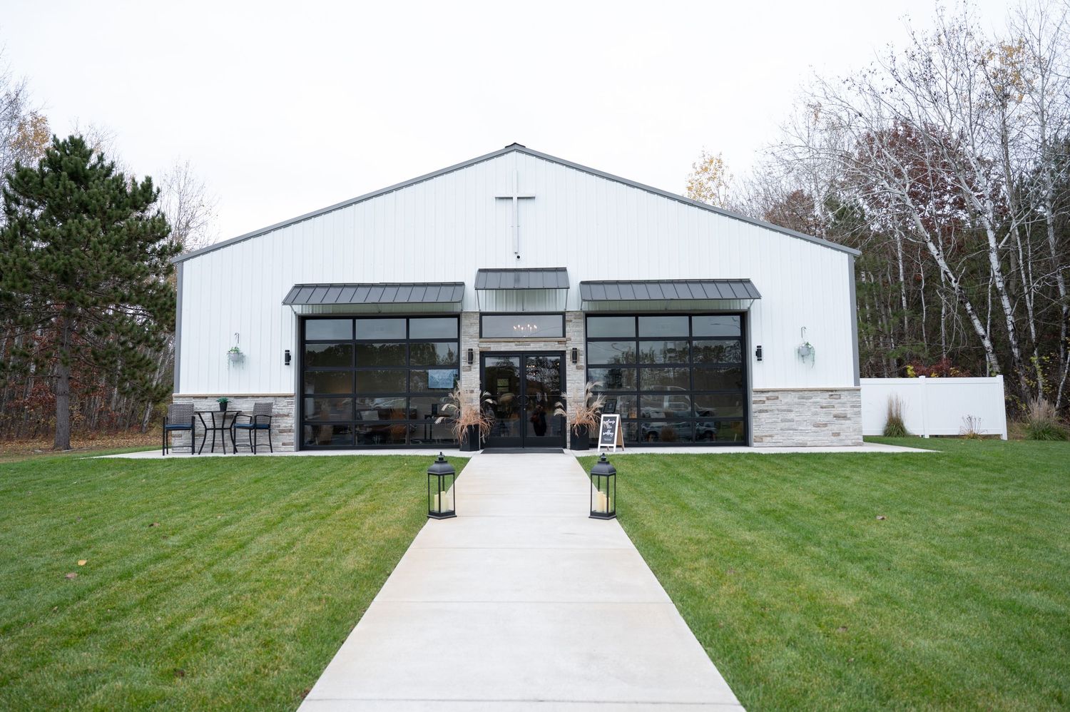 Large white storage buildings with garage doors sit on a well-maintained grassy lawn under cloudy skies.