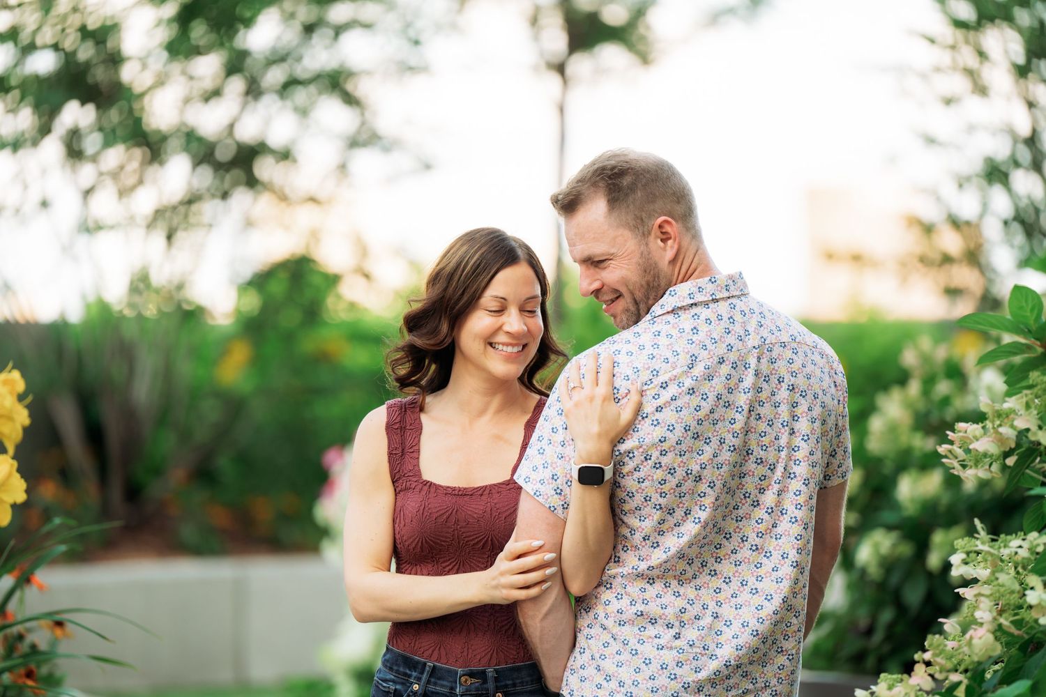 A couple shares a tender moment while dancing together in a beautiful outdoor garden setting.