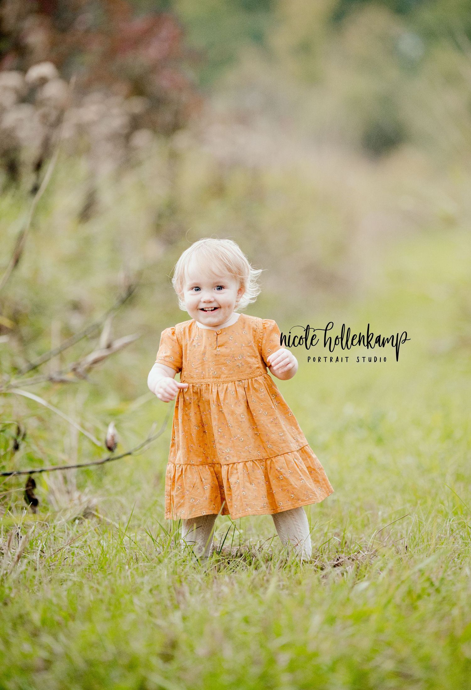 Young child in orange dress smiling joyfully in outdoor garden setting.