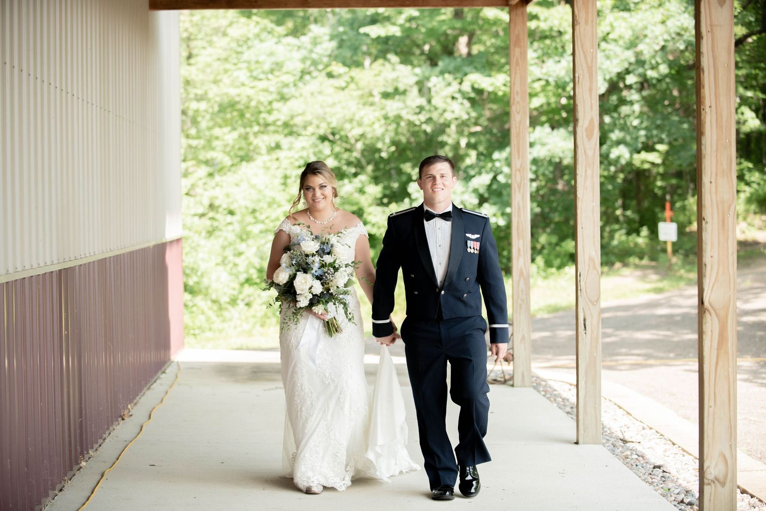 Wedding couple walking and interacting under a covered wooden walkway. Zimmerman MN Weddings