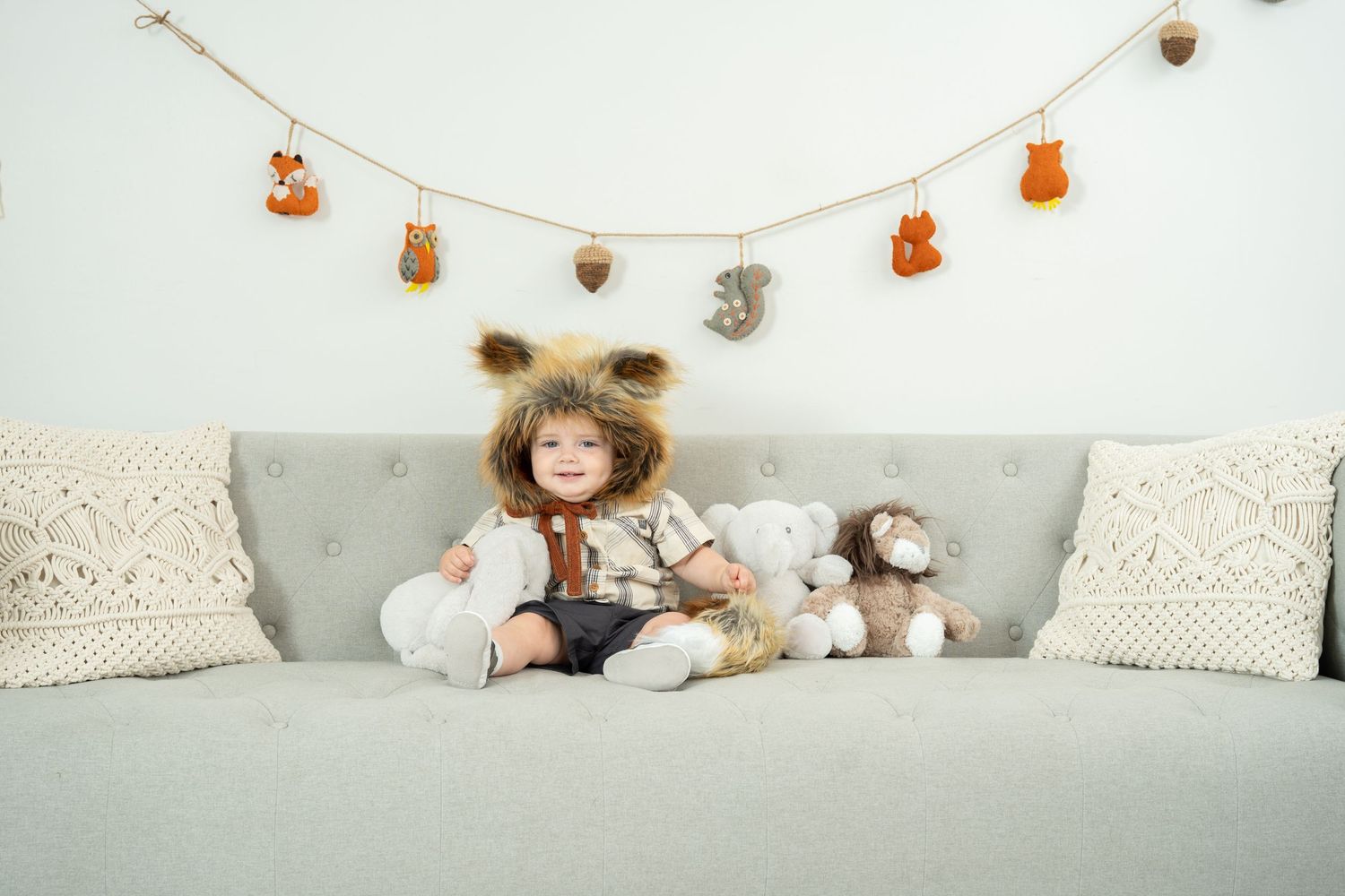 A cozy nursery scene with stuffed animals arranged on a white bed against a light gray wall.